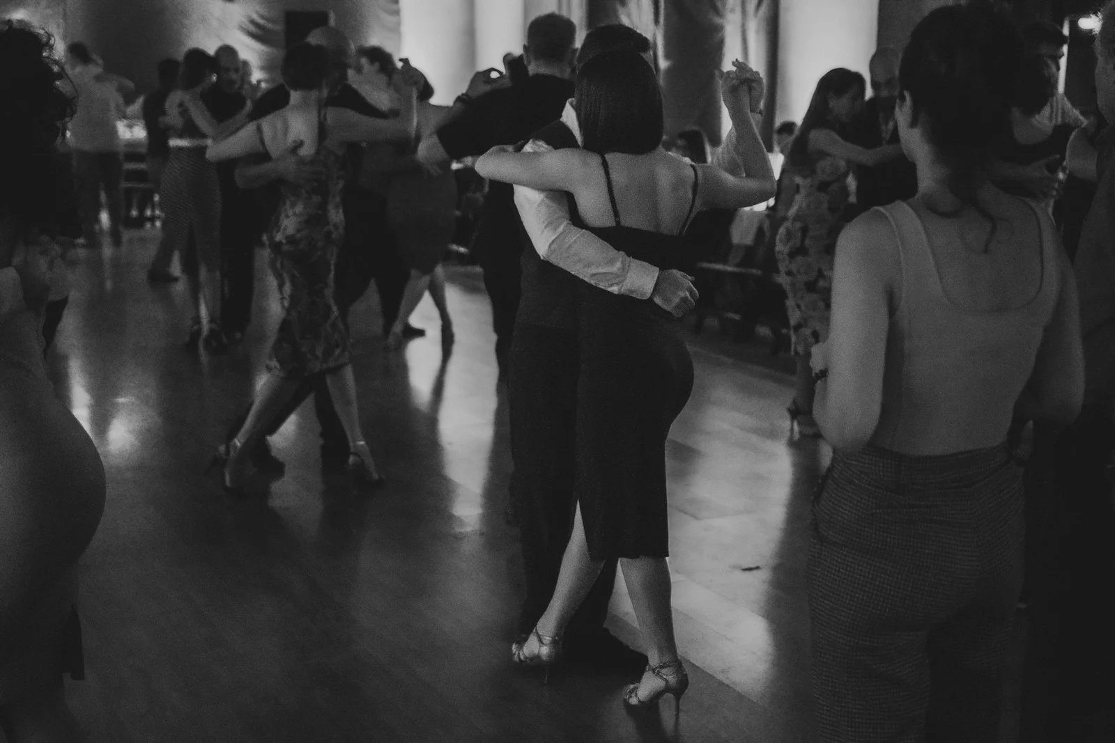 Parejas bailando bachata en sala poco iluminada